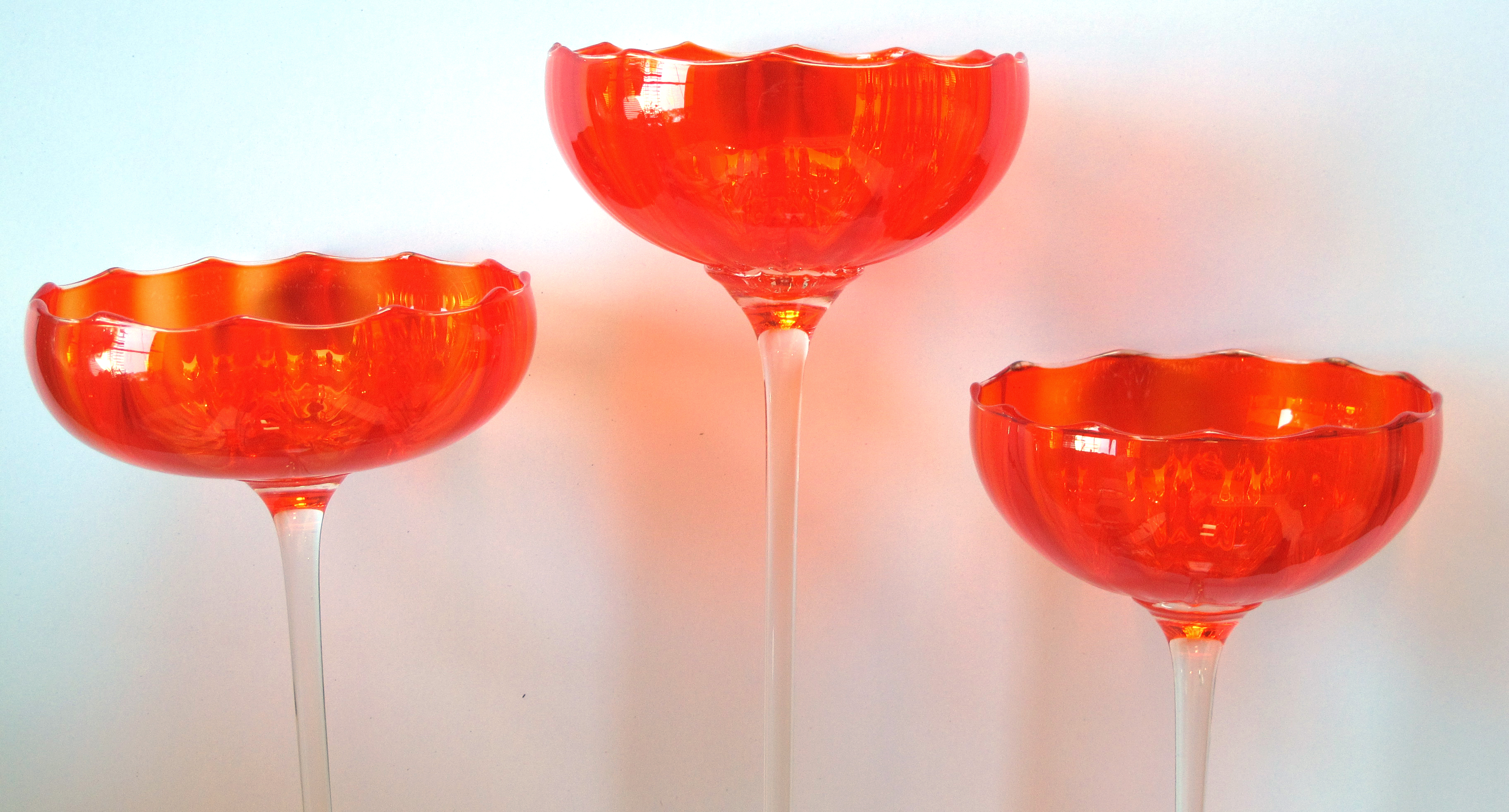 a vibrant set of 3 murano 1960's orange glass compotes on clear glass
