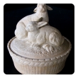 a charming french beige-colored pottery basket-weave bowl with cover adorned with two rabbits