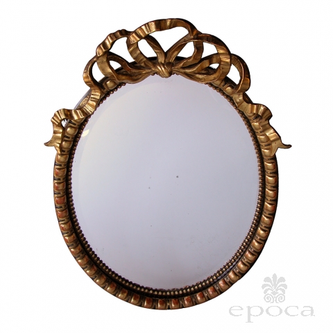 a festive and large-scaled napoleon iii ebonized and giltwood oval mirror with a carved ribbon crest